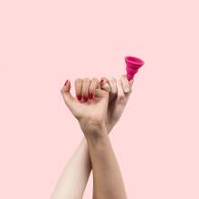 Image: manicured hands holding menstrual cup