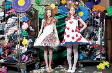 image: two students model dresses that they made from donated textile waste