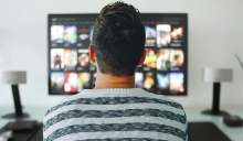 Back of adult man watching tv screen