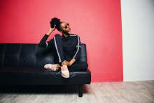 Black woman sitting on sofa in tracksuit
