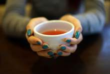 Hands holding white cup of tea