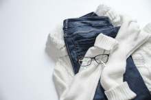 Wite jumper, blue jeans and glasses in a pile on floor