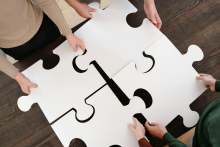 People holding large jigsaw pieces slotting together