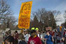 Crowd protest, one banner reads "I'm not lovin poverty wages"