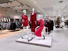 Three mannequins in red clothing inside a clothing store