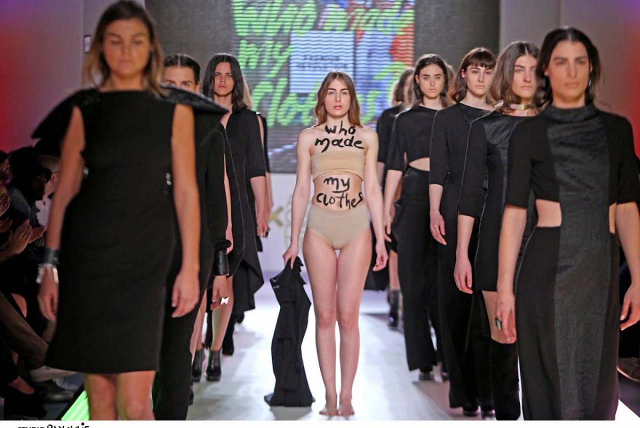 Image: near naked model surrounded by models dressed in black her body reads who made my clothes