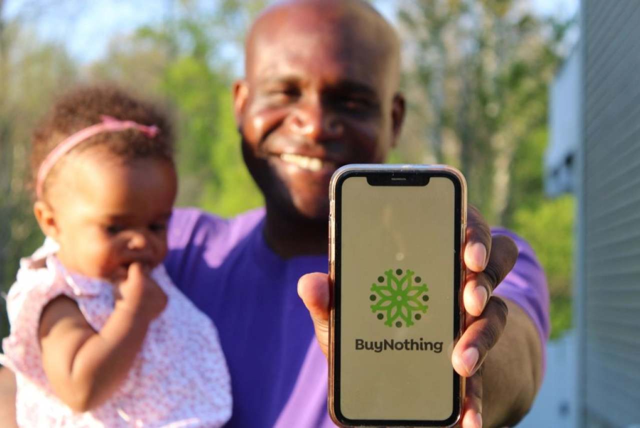 Man holding baby and mobile phone with buy nothing logo