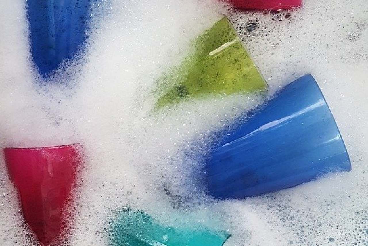 Multi coloured glasses in washing up bowl