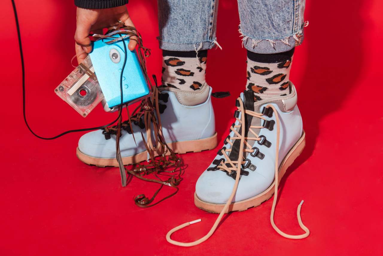 1980s boots and clothes with person holding tape cassette unspooled
