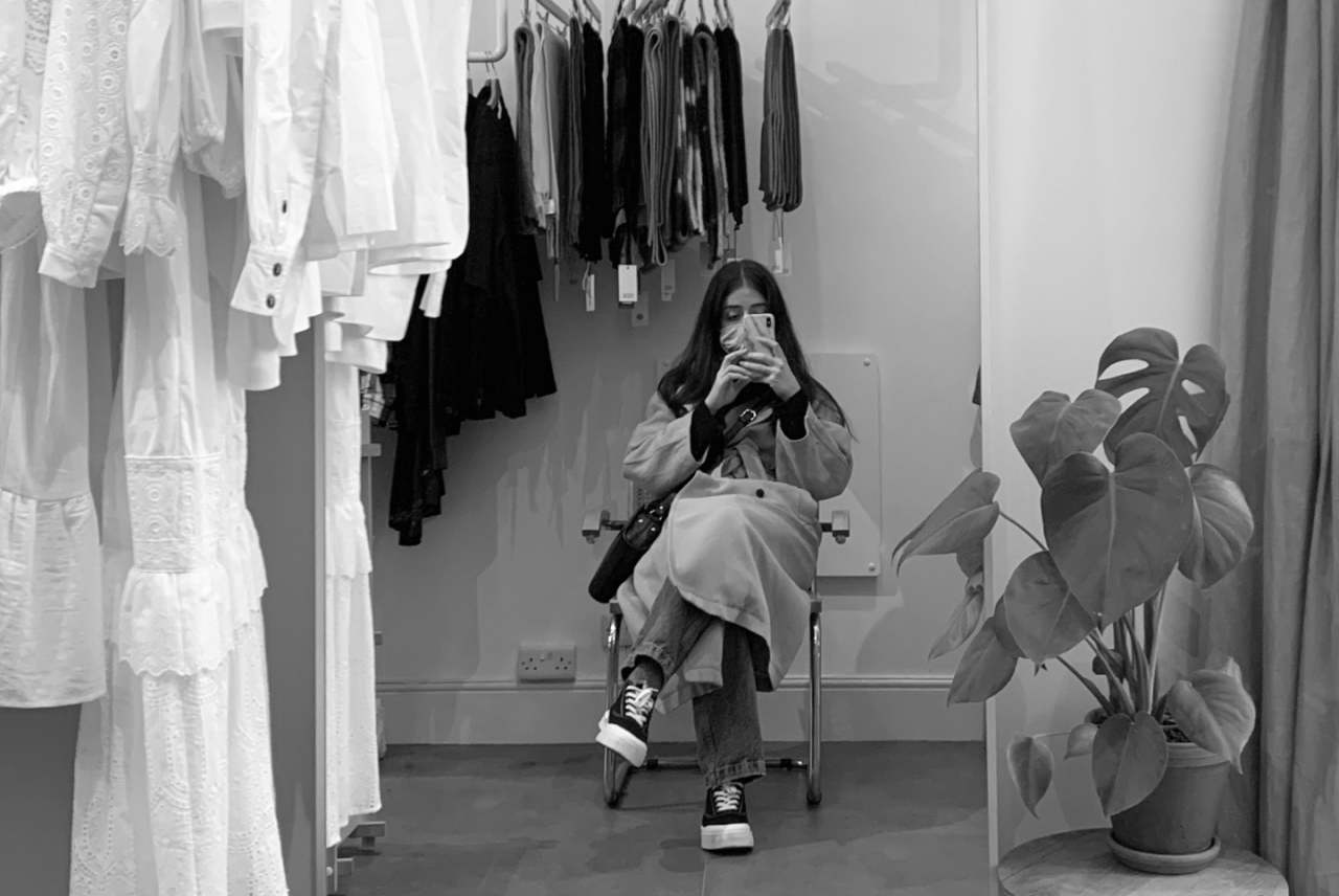Black and white image of women sitting in changing room taking photo
