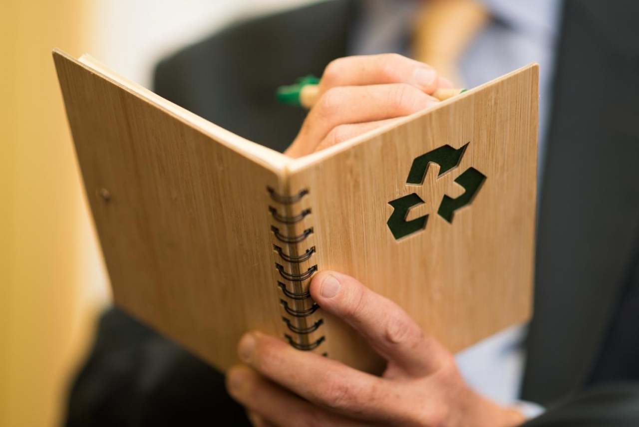 Person holding a wooden notebook with recycling logo on front