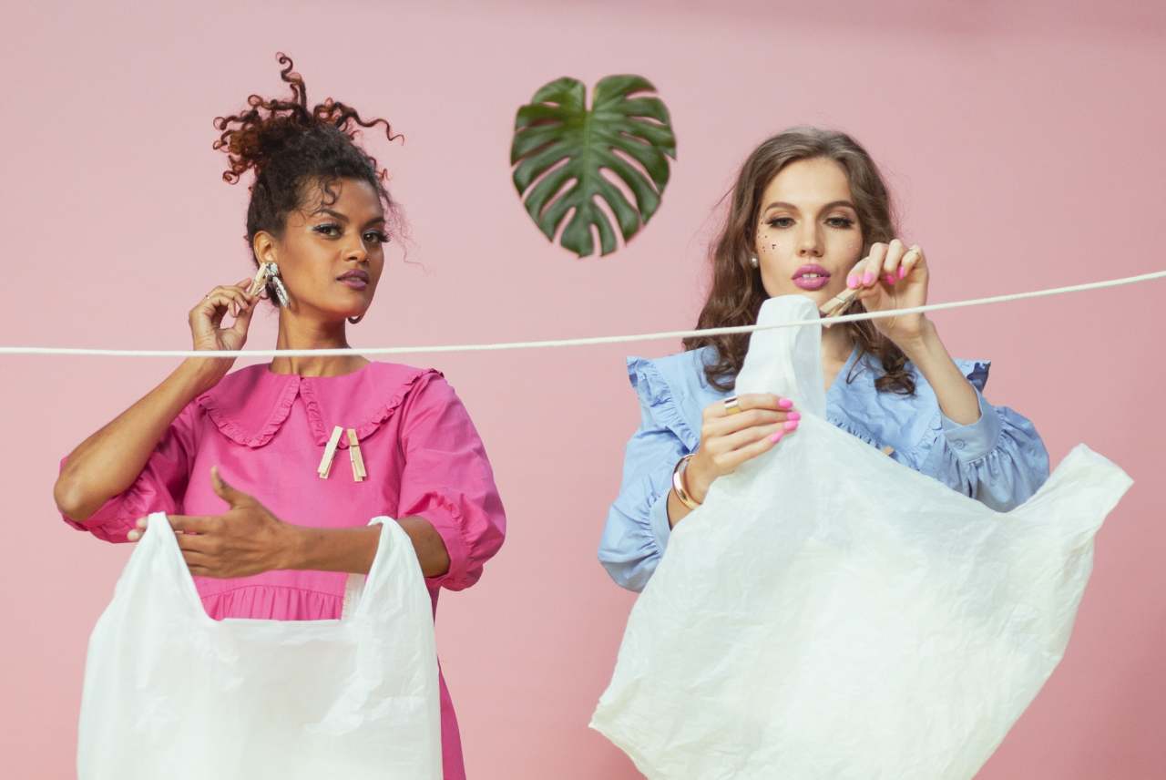 Two women hanging plastic bags on a washing line
