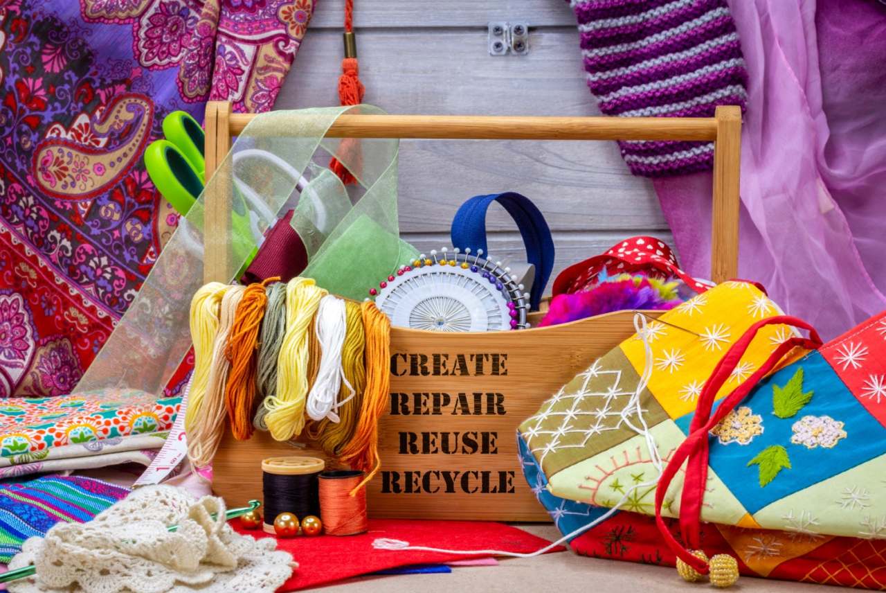 Lots of materials around a sewing box with the words 'create repair reuse recycle'