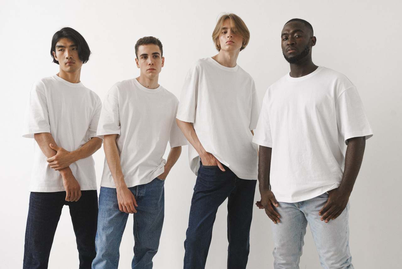 Four men wearing white t-shirts and denim jeans
