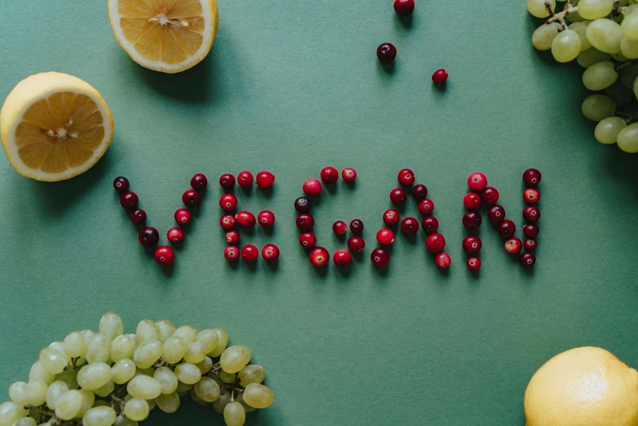 The word vegan spelt out in cranberries, with lemons and grapes also in picture