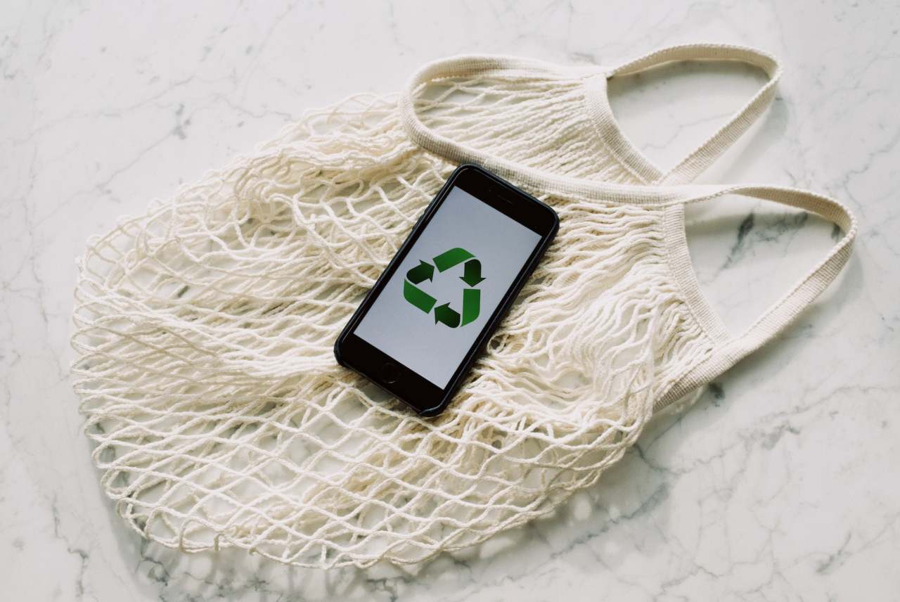 white cotton string bag with mobile phone displaying recycle logo