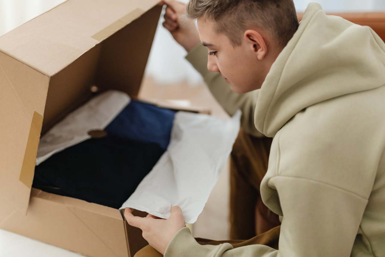 Person looking in a cardboard parcel with clothing inside