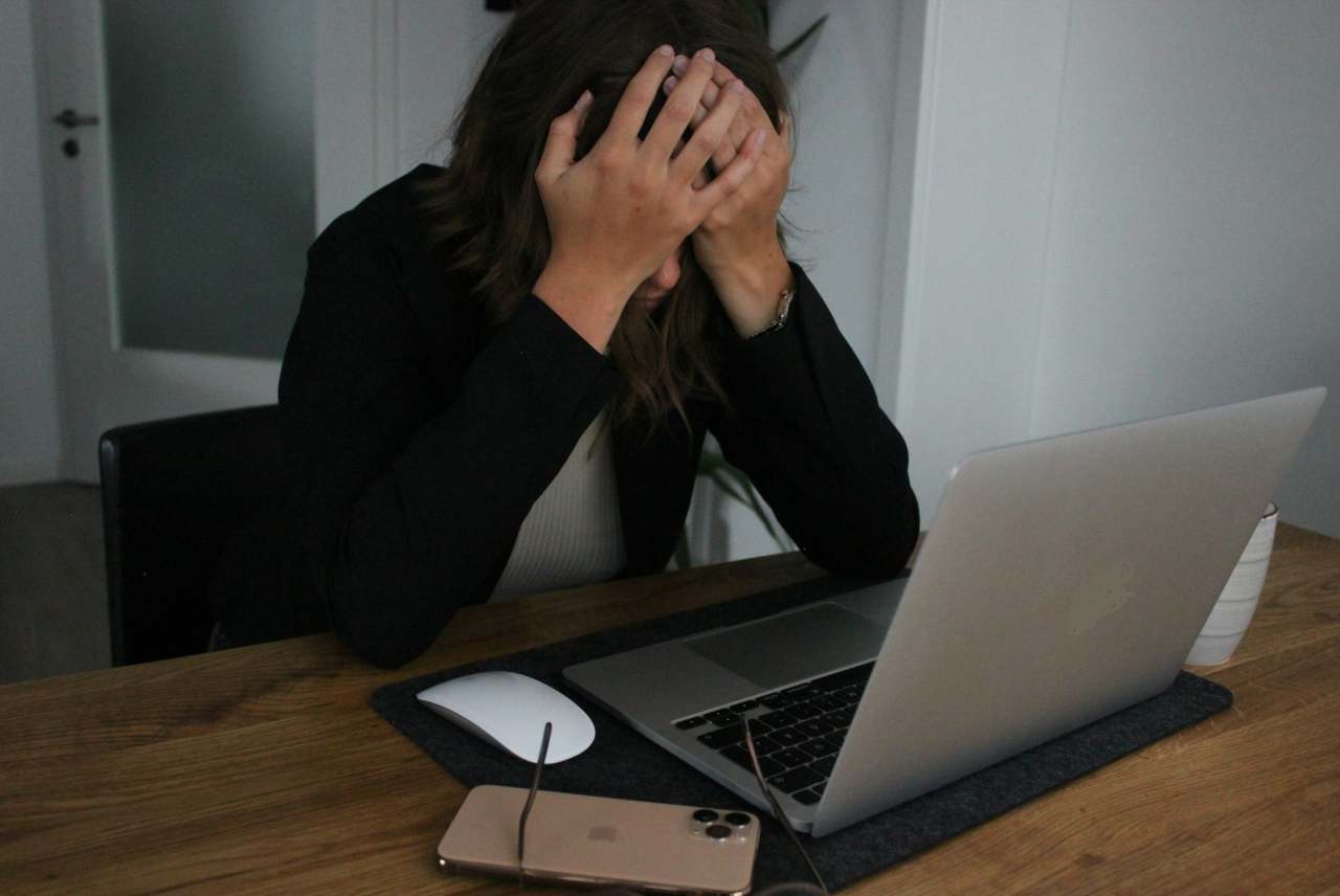 Woman with head in hands sat infront of laptop