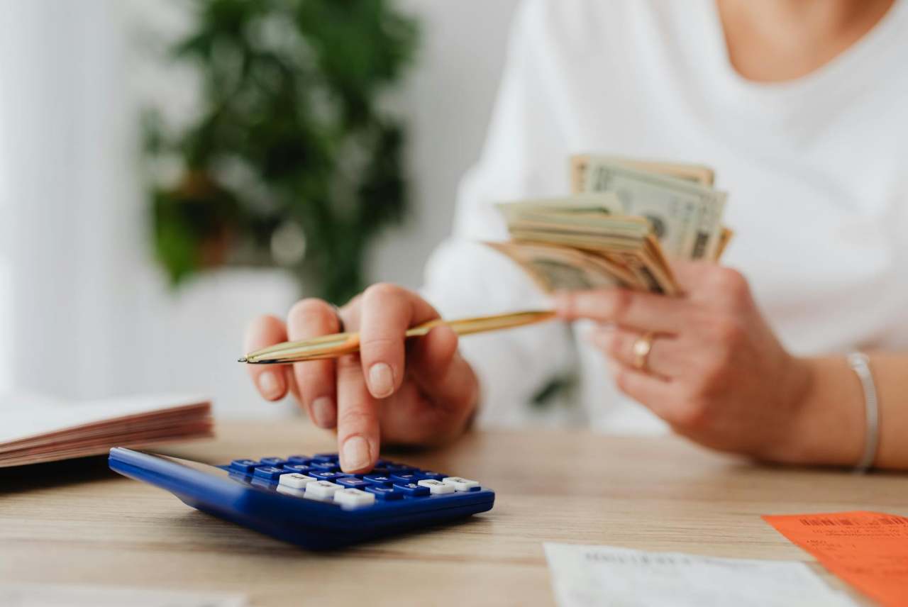 Person counting money and using calculator