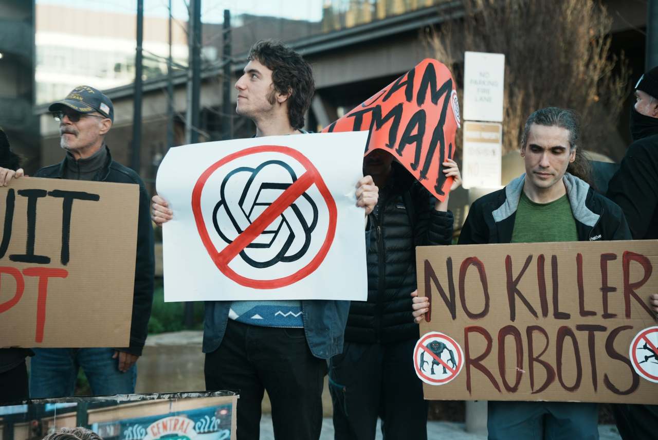 People holding banners including 'quitGPT' and 'no killer robots'