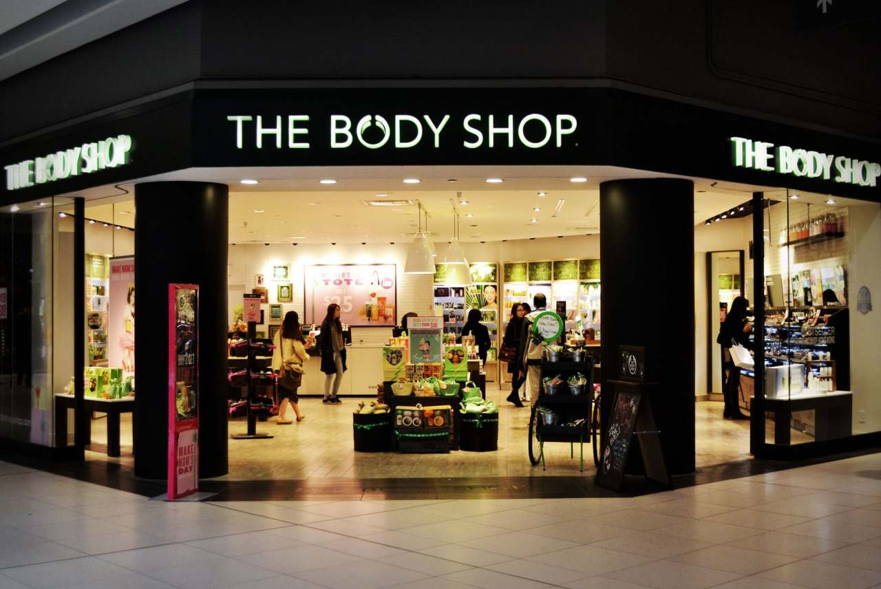 Front view of The Body Shop store with lights on inside