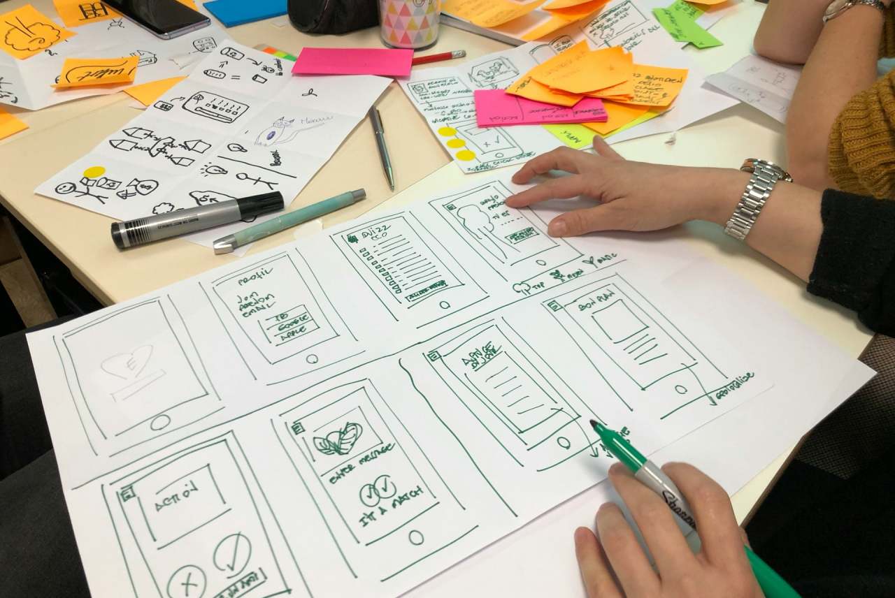 View of person planning a redesign project on large piece of paper with other papers on the desk