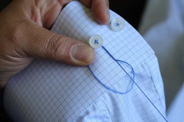 Person sewing button on shirt