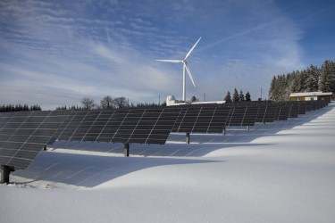 Solar panels and wind farm on snowy ground