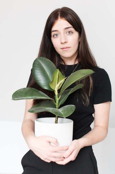 Besma holding a small rubber plant