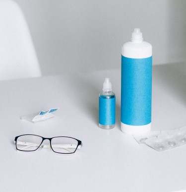 Glasses, contact lenses and lens solutions in bottles on table
