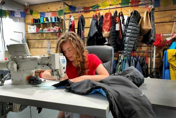 Woman repairing waterproof jacket with sewing machine