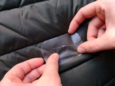 Person sewing patch onto an insulated jacket