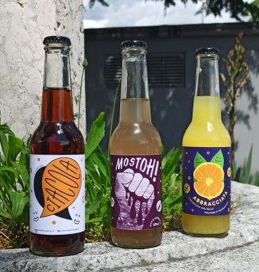 Three bottles of fizzy drinks on stone wall outside