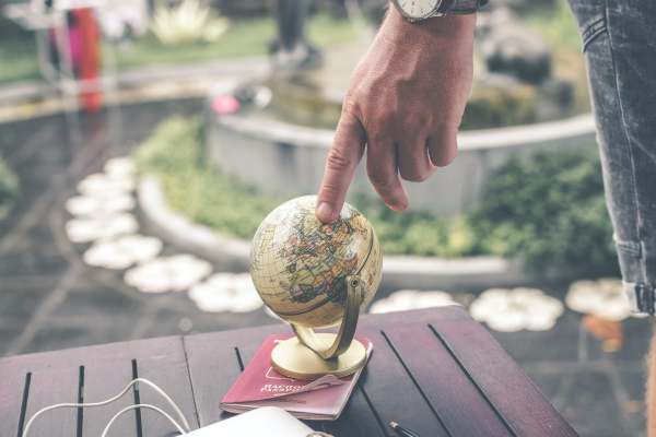 Person with finger on a small globe which is on a passport