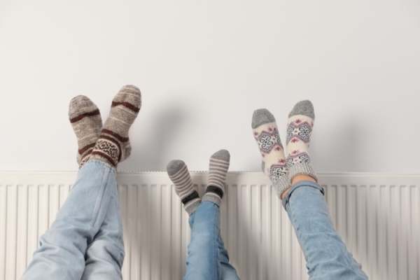 Radiator with three pairs of feet in socks resting on it