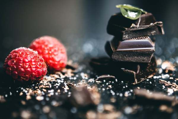 Dark chocolate squares with mint leaf and raspberries