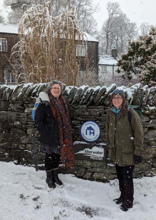 Two women outside stone building in snow