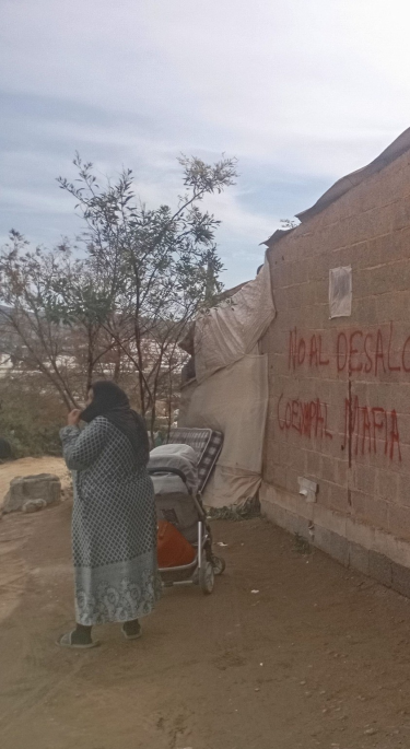 Woman and pushchair by wall and tarpaulin covering