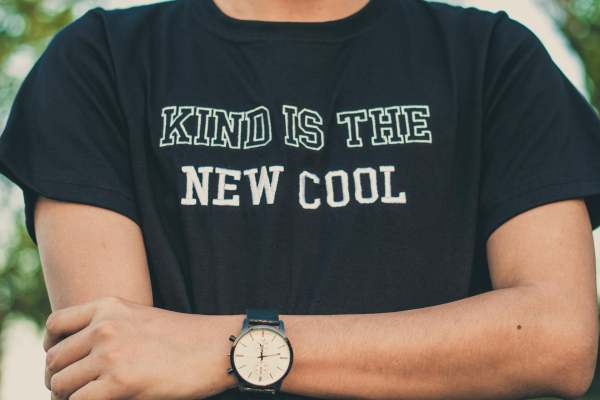 Person wearing black tshirt with words 'Kind is the new cool' on it