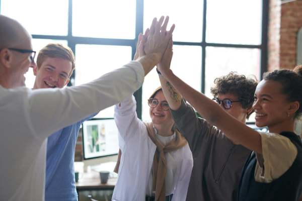 Group of five people with hands raised in high five position, together