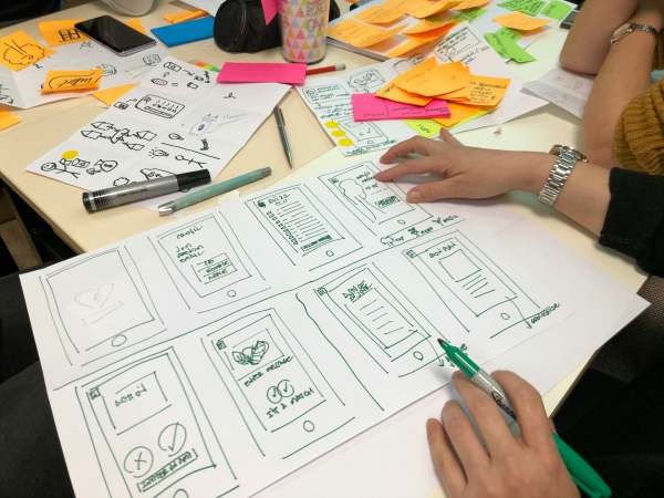 View of person planning a redesign project on large piece of paper with other papers on the desk