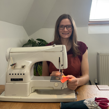 Woman sitting at sewing machine in room in house